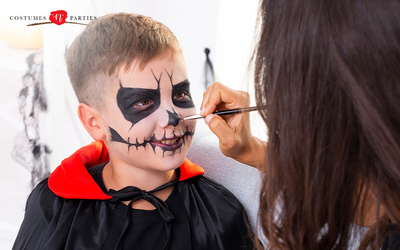 Woman painting a child’s face for Halloween.